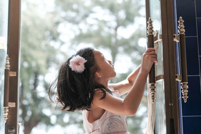 Side view of young woman cleaning window