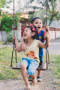 Full length of happy girl playing on swing at playground