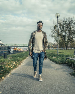 Full length portrait of young man standing against sky