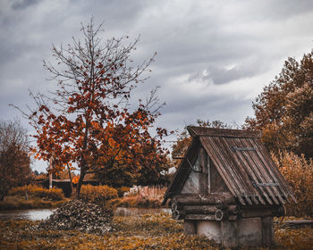 Trees by building against sky during autumn