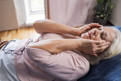 Low section of man lying on bed at home