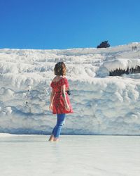 Woman standing in lake against glaciers during winter