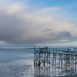 Scenic view of sea and fishing hut against sky