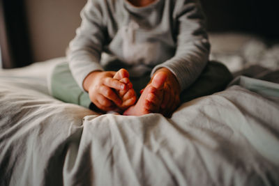 Midsection of person relaxing on bed at home