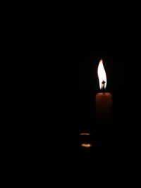 Close-up of lit candle in dark room