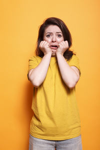 Young woman looking away against yellow background