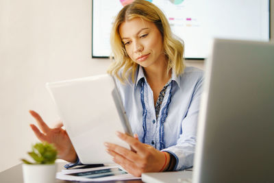 Young woman using phone while sitting on table