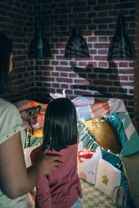 Unrecognizable woman and girl having fun together playing in shade show on living room
