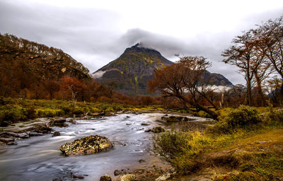 Stream flowing through rocks against sky