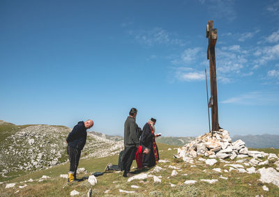 People by cross on mountain