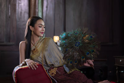 Young woman looking away while sitting on display