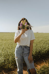 Rear view of woman standing on field against clear sky