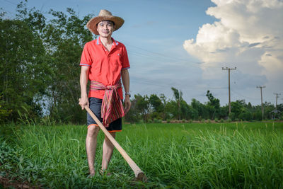 Portrait of senior man standing on field against sky