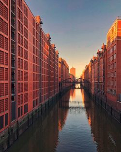 Bridge over river amidst buildings in city against sky