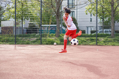 Girl soccer player jumping with soccer ball in the air