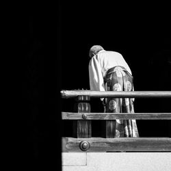 Rear view of man leaning on railing