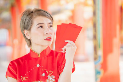 Portrait of young woman holding red umbrella