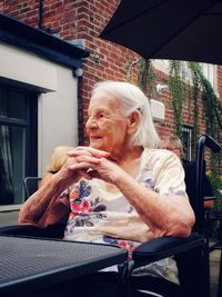 Senior woman with hands clasped sitting in restaurant