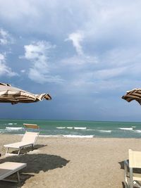 Deck chairs on beach against sky