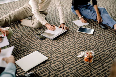 Male and female business professionals writing on papers during conference at convention center