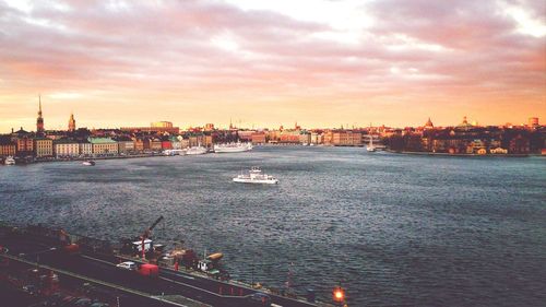 Boats at harbor against cloudy sky