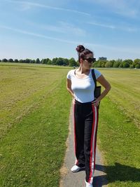 Full length of woman with hands on hip standing at park against sky