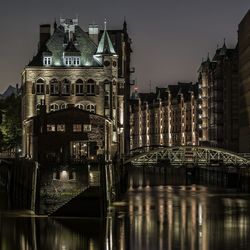 Illuminated building by canal at night