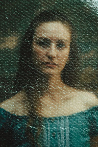 Close-up portrait of woman seen through glass window