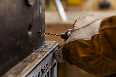 Close-up of person working on metal grate