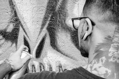 Close-up of young man making graffiti on wall