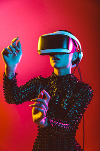 Woman wearing eyeglasses standing against red background