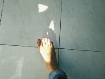 Low section of person standing on tiled floor