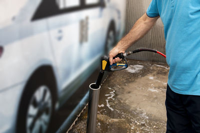 Car washing. mature man cleaning automobile with high water pressure. self service