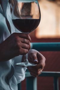 Midsection of woman holding wineglass