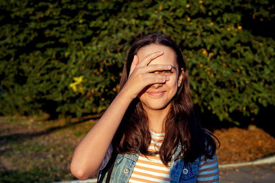 Portrait of young woman against trees