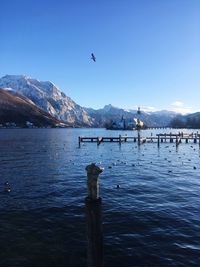 Scenic view of lake and snowcapped mountains against blue sky