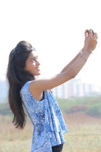 Young woman standing against clear sky