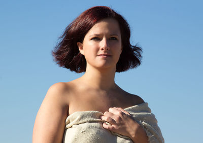 Portrait of young woman against blue sky