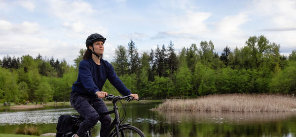 Full length of man on bicycle by lake against sky