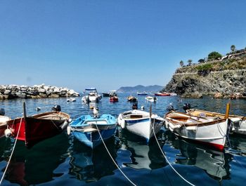 Sailboats moored on sea against clear blue sky