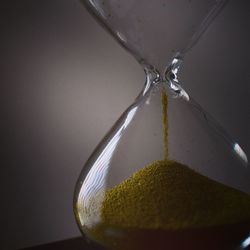 Close-up of hourglass on table against gray background