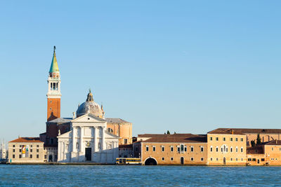 View of buildings by canal against clear sky