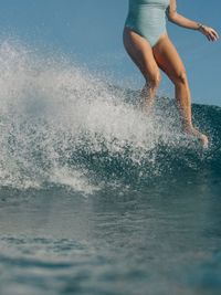 Low section of man surfing in sea