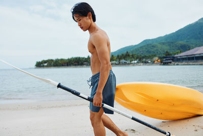 Rear view of shirtless man standing in boat