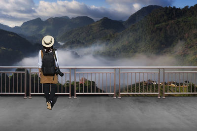 Woman standing by railing against mountain