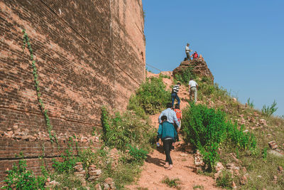 Rear view of people walking on mountain against sky