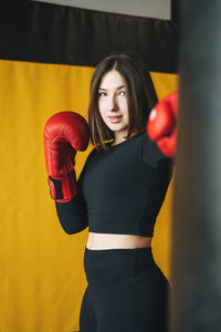 Young brunette woman in black wear engaged boxing training in the fitness club gym