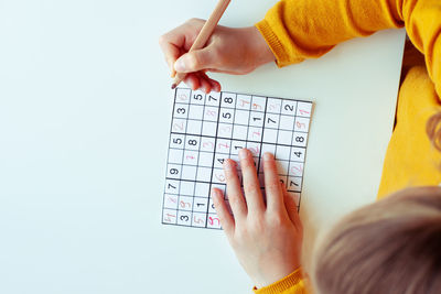 Directly above shot of girl doing sudoku puzzle