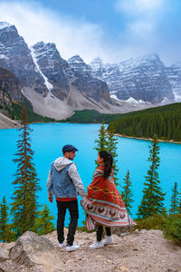 Rear view of women standing by lake against mountains