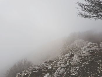 Snow covered landscape against sky during foggy weather